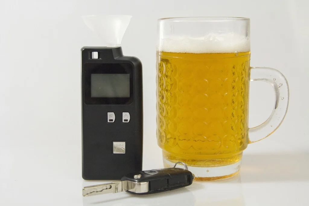 Etilómetro junto a una jarra de cerveza y unas llaves de coche