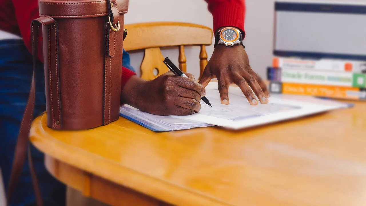 Persona firmando un documento sobre una mesa