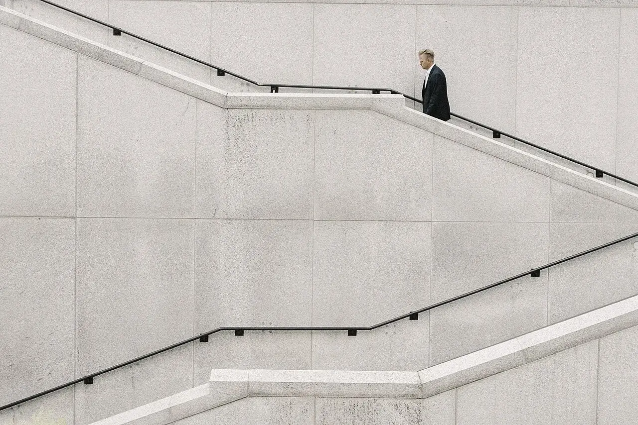 Hombre con traje subiendo la escalera exterior de un edificio