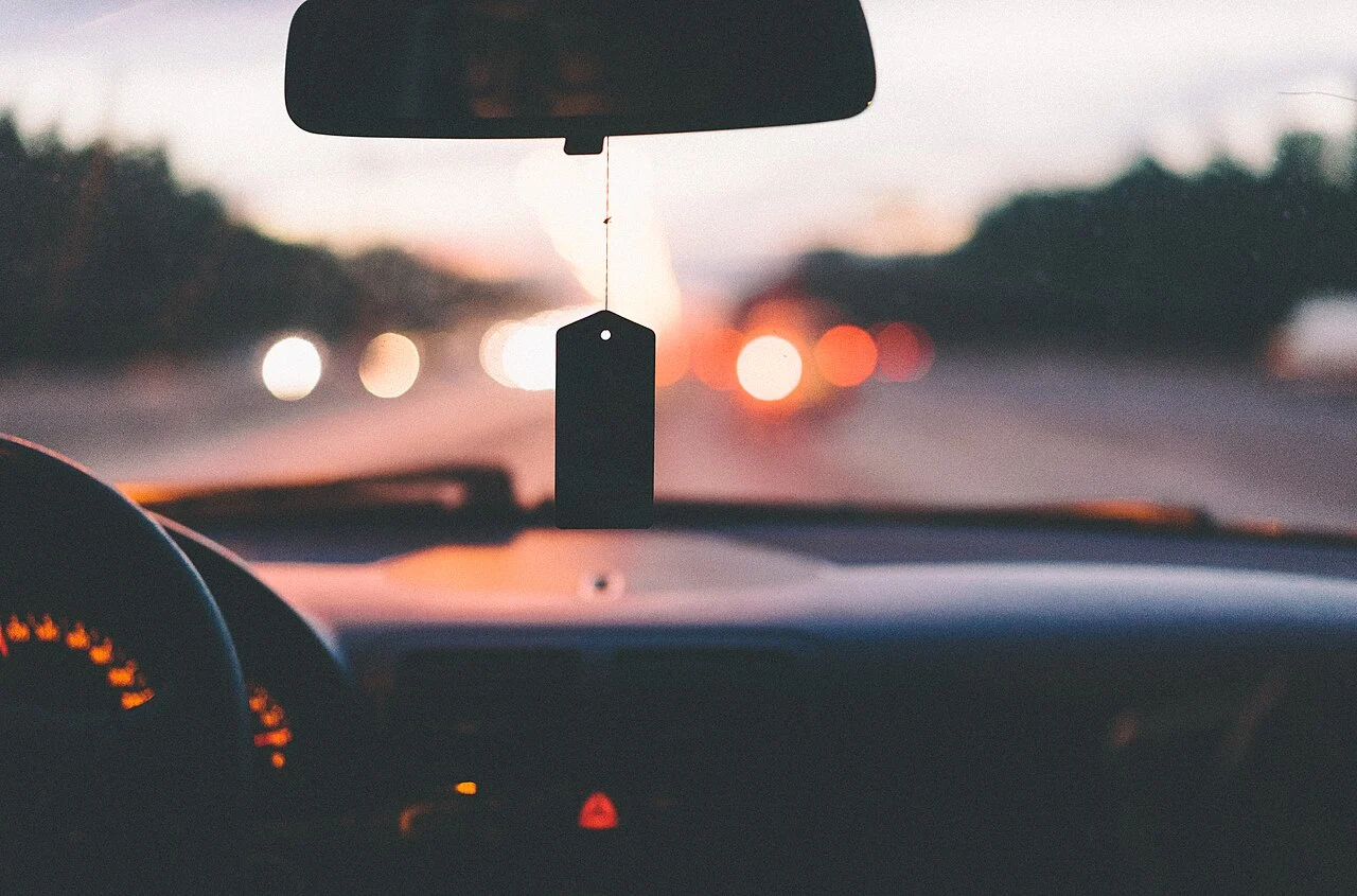 Salpicadero de un coche en carretera al atardecer con las luces desenfocadas