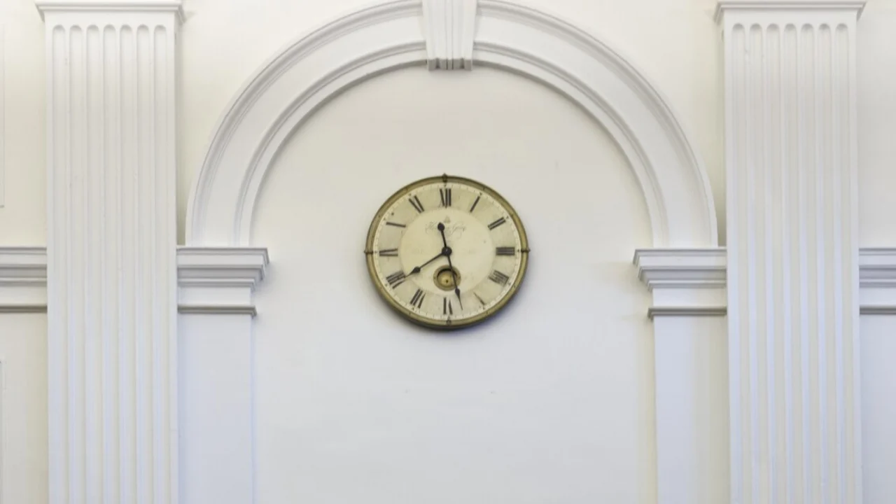 Reloj de pared entre dos pilastras blancas en una sala de vistas